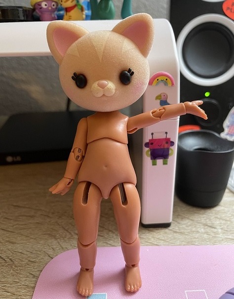 A cat head on a small string-jointed doll body.